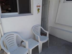 twee witte stoelen naast een raam bij Pablo Guess House in Cap-Haïtien