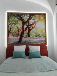a painting of a tree above a bed at Guesthouse Alentejo in Évora