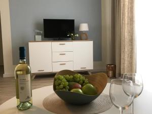 una bottiglia di vino e un cesto di frutta su un tavolo di SEASIDE APARTMENTS - BEACHHOUSE WAVE a Eckernförde