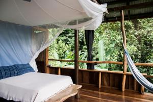 a bedroom with a canopy bed and a window at La Loma Jungle Lodge and Chocolate Farm in Bocas Town