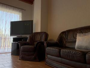 - un salon avec 2 fauteuils en cuir et une télévision à écran plat dans l'établissement Zamárdi Balaton View, à Zamárdi
