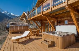 a deck with a hot tub and a grill on a house at The Vaujany Mountain Lodge in Vaujany