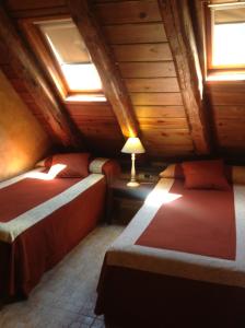 a bedroom with two beds in a wooden attic at Pradets in Vielha