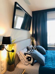 1 dormitorio con cama con almohadas azules y espejo en Aquamarina Onyx Blue, en Międzyzdroje