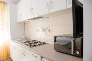 a kitchen with white cabinets and a stove top oven at Garsoniera Jad in Târgu Ocna
