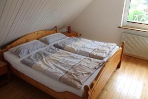 ein Schlafzimmer mit einem Holzbett mit weißer Bettwäsche in der Unterkunft Ferienwohnungen im Gästehaus Sieberns in Carolinensiel