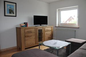 ein Wohnzimmer mit einem Flachbild-TV auf einem Holzschrank in der Unterkunft Ferienwohnungen im Gästehaus Sieberns in Carolinensiel