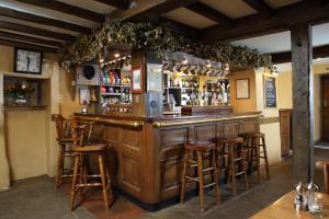 a bar with wooden bar stools in a pub at Eight Bells Inn in Chipping Campden