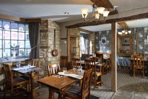 a restaurant with wooden tables and chairs in a room at Eight Bells Inn in Chipping Campden