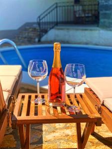 tres copas de vino y una botella en una mesa de madera en Holiday Home Deni, en Roč
