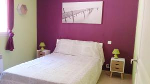 - une chambre avec un lit blanc et un mur violet dans l'établissement Villa Les hauts de Benista, à Porticcio