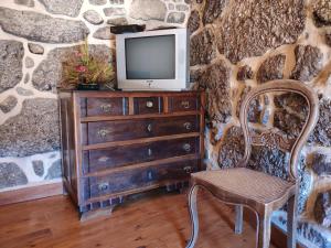 a tv sitting on top of a dresser with a chair at Casa Padre Alexandre in Covide