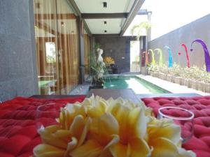 a table with red chairs and a yellow flower in front of a pool at Bali Golden Elephant Boutique Villa in Jimbaran