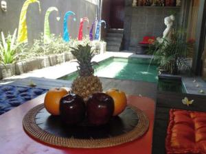 a plate of fruit on a table in front of a pool at Bali Golden Elephant Boutique Villa in Jimbaran