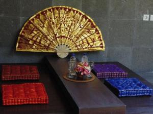uma mesa com uma ventoinha e alguns assentos vermelhos e azuis em Bali Golden Elephant Boutique Villa em Jimbaran