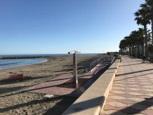 einen Strand mit einer Reihe von Bänken und Palmen in der Unterkunft Fercamar Costacabana in Almería