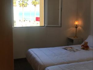 a teddy bear sitting on a bed in a room with a window at Fercamar Costacabana in Almería