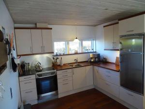 a kitchen with white cabinets and a stainless steel refrigerator at Fin lejlighed med lukket have in Skagen