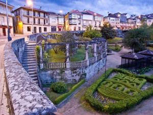 una vieja pared de piedra con un jardín en una ciudad en Chalet Adosado Allariz, en Allariz