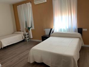 Un dormitorio con dos camas y una ventana. en Hostal Restaurante Rufino, en Berlanga