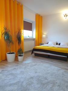 Zajazd WiK في Åšlesin: غرفة نوم مع ستائر برتقالية وسرير بالنباتات