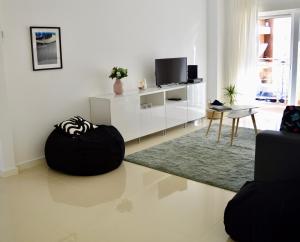 uma sala de estar com televisão e um repousa-pés preto em Charming 3 Bedroom Apartment Close to Historic Center-Lagos em Lagos