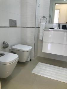 een witte badkamer met een toilet en een wastafel bij Charming 3 Bedroom Apartment Close to Historic Center-Lagos in Lagos