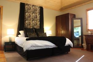 a bedroom with a bed with a black and white blanket at Linden Gardens Rainforest Retreat in Mount Dandenong