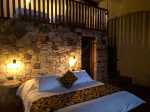 a bedroom with a bed with a stone wall at Mamaq Tambo Lodge in Cocachimba