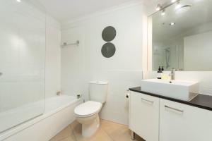 a white bathroom with a toilet and a sink at Awesome Downtown Location - park the car and walk to everything ! in Mount Maunganui +11 photos