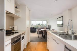 a kitchen with white cabinets and a dining room at Awesome Downtown Location - park the car and walk to everything ! in Mount Maunganui