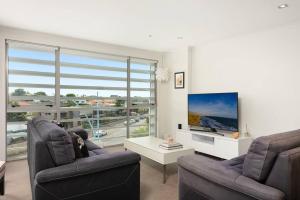 a living room with two chairs and a flat screen tv at Awesome Downtown Location - park the car and walk to everything ! in Mount Maunganui