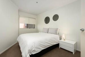 a white bedroom with a white bed and a white table at Awesome Downtown Location - park the car and walk to everything ! in Mount Maunganui