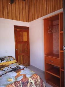 1 dormitorio con 1 cama y armario de madera en Estancia Santa Teresita (EST), en Nosara