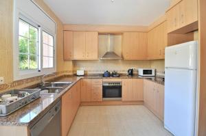 eine Küche mit Holzschränken und einem weißen Kühlschrank in der Unterkunft Villa Genova in Lloret de Mar