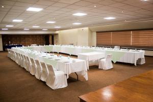 a large banquet hall with white tables and white chairs at Hotel Mirage in Querétaro