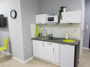 a white kitchen with a sink and a microwave at Kawalerka w kamienicy na Starówce in Gdańsk