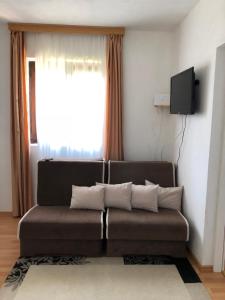 a living room with a brown couch in front of a window at Apartman Jezerce 71 in Plitvička Jezera