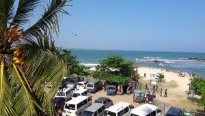 un grupo de coches estacionados en una playa junto al océano en Tangalle Rest House, en Tangalle