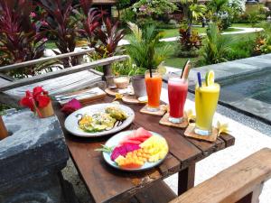 una mesa de madera con platos de comida y bebidas. en Kubu Kangin Resort, en Amed