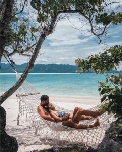 吉利特拉旺安的住宿－彭杜克桑蒂酒店，两个人躺在海滩上的吊床上