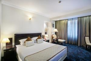 a hotel room with a large bed and a desk at Hotel Sarina in Dhaka