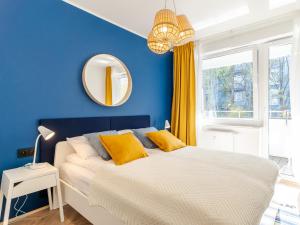 a blue bedroom with a bed with yellow pillows at Apartament SURF SurfingBird Kołobrzeg in Kołobrzeg +31 photos