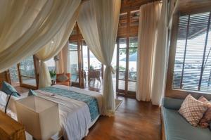 a bedroom with a bed in a room with windows at Bayview Gardens Hotel in Labuan Bajo