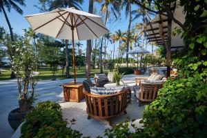 een patio met stoelen, een parasol en palmbomen bij Pondok Santi Estate in Gili Trawangan