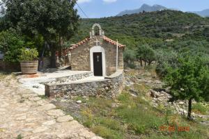 a small stone chapel with a black door on a hill at Ouranias Studios in Kardamyli