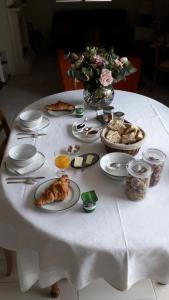 a white table with plates of food and a vase of flowers at Chambre d'hôtes - La Maison de Jane in Jullouville-les-Pins