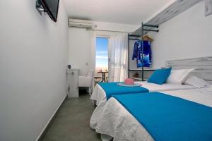 a bedroom with a blue and white bed and a window at La Palmera. El amanecer en el Parque Natural in Agua Amarga