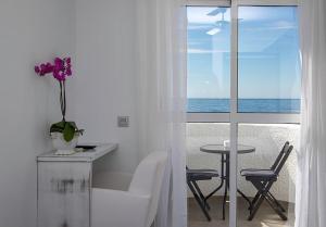 Habitación blanca con mesa y jarrón con flores púrpuras en La Palmera. El amanecer en el Parque Natural, en Agua Amarga