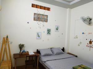 - une chambre avec un lit, un bureau et des photos sur le mur dans l'établissement S Phuot Ban Me Homestay, à Buôn Ma Thuột
